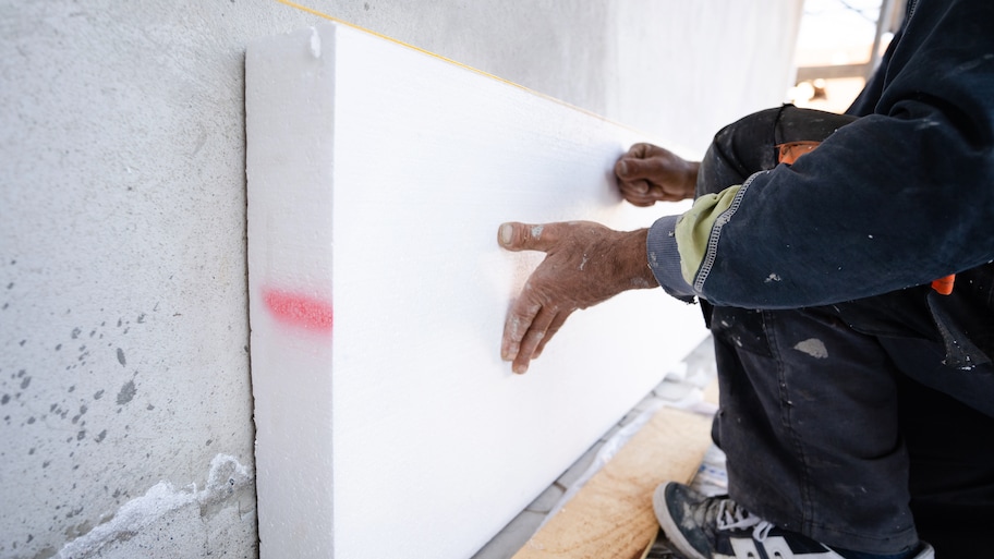 Workers installing rigid foam insulation on the side of a building